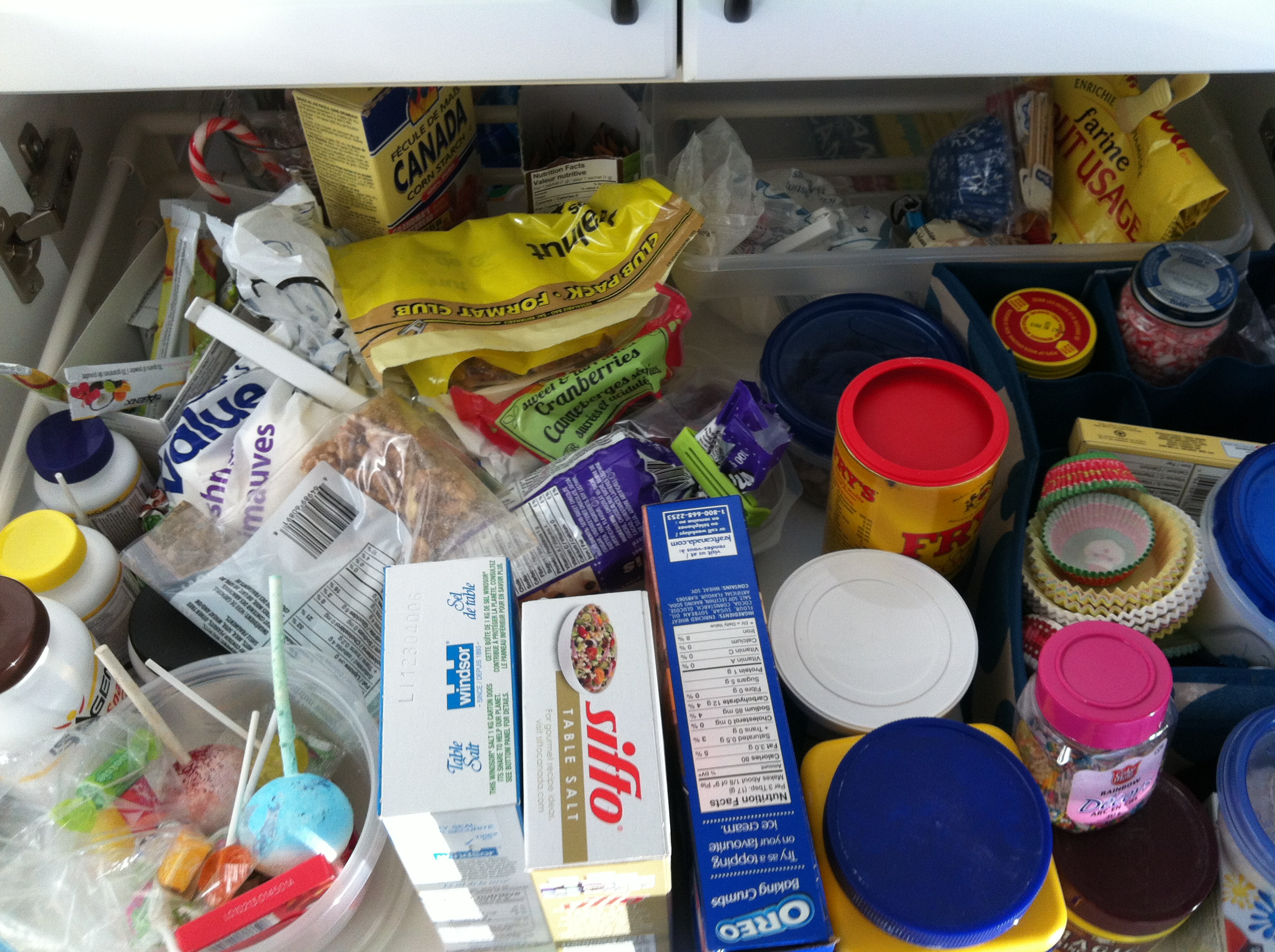 An opened pantry drawer with items scattered about inside.