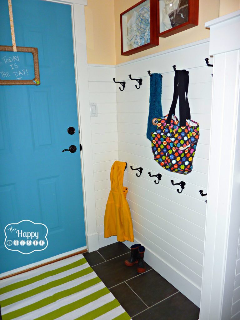 A yellow coat and bags hanging on the hooks by the front door.