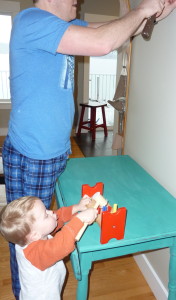 A Dad and his son helping put up the mirror.
