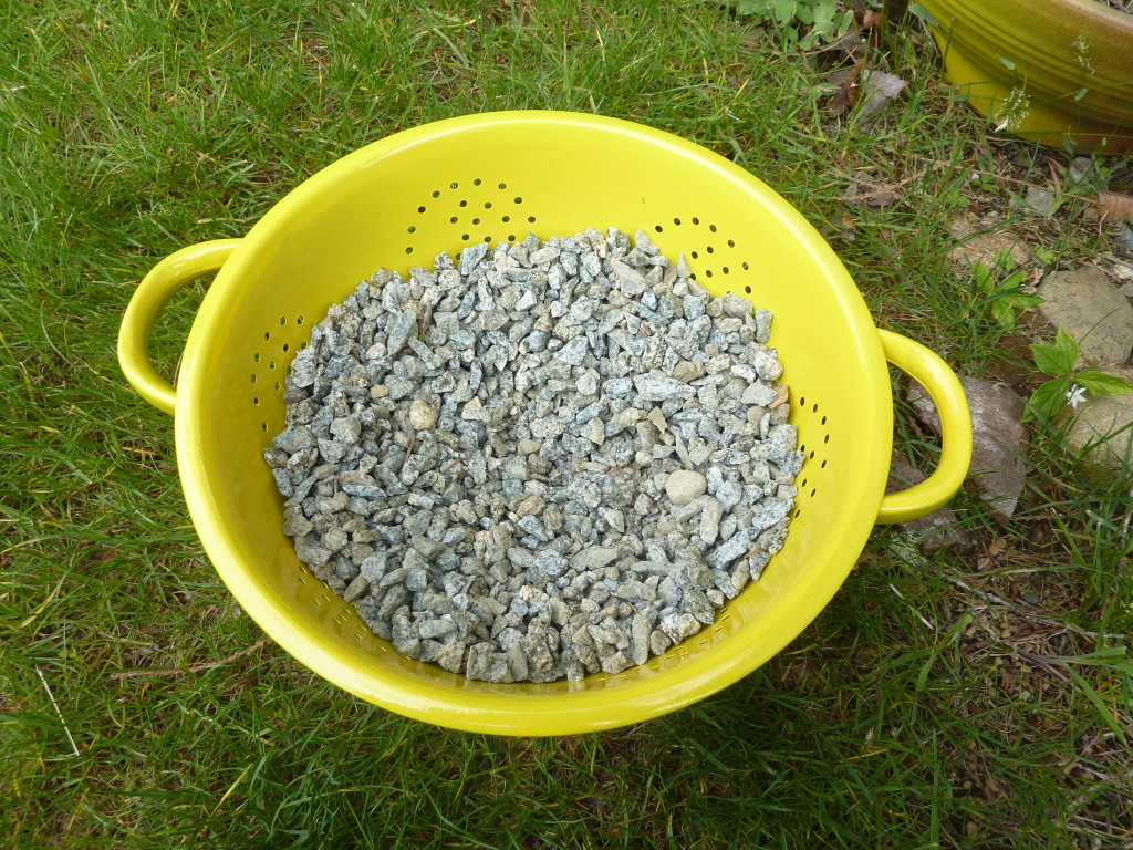 Putting gravel in the bottom of the collander.