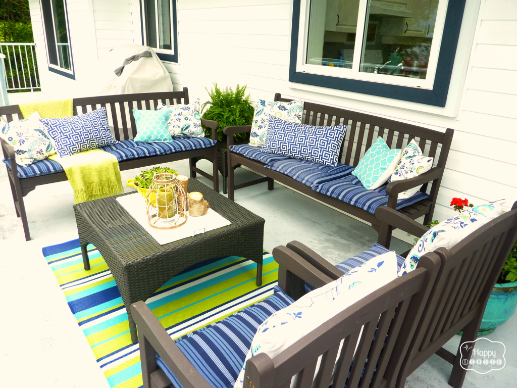 Outdoor chairs and cushions on the deck with blue and green rug.