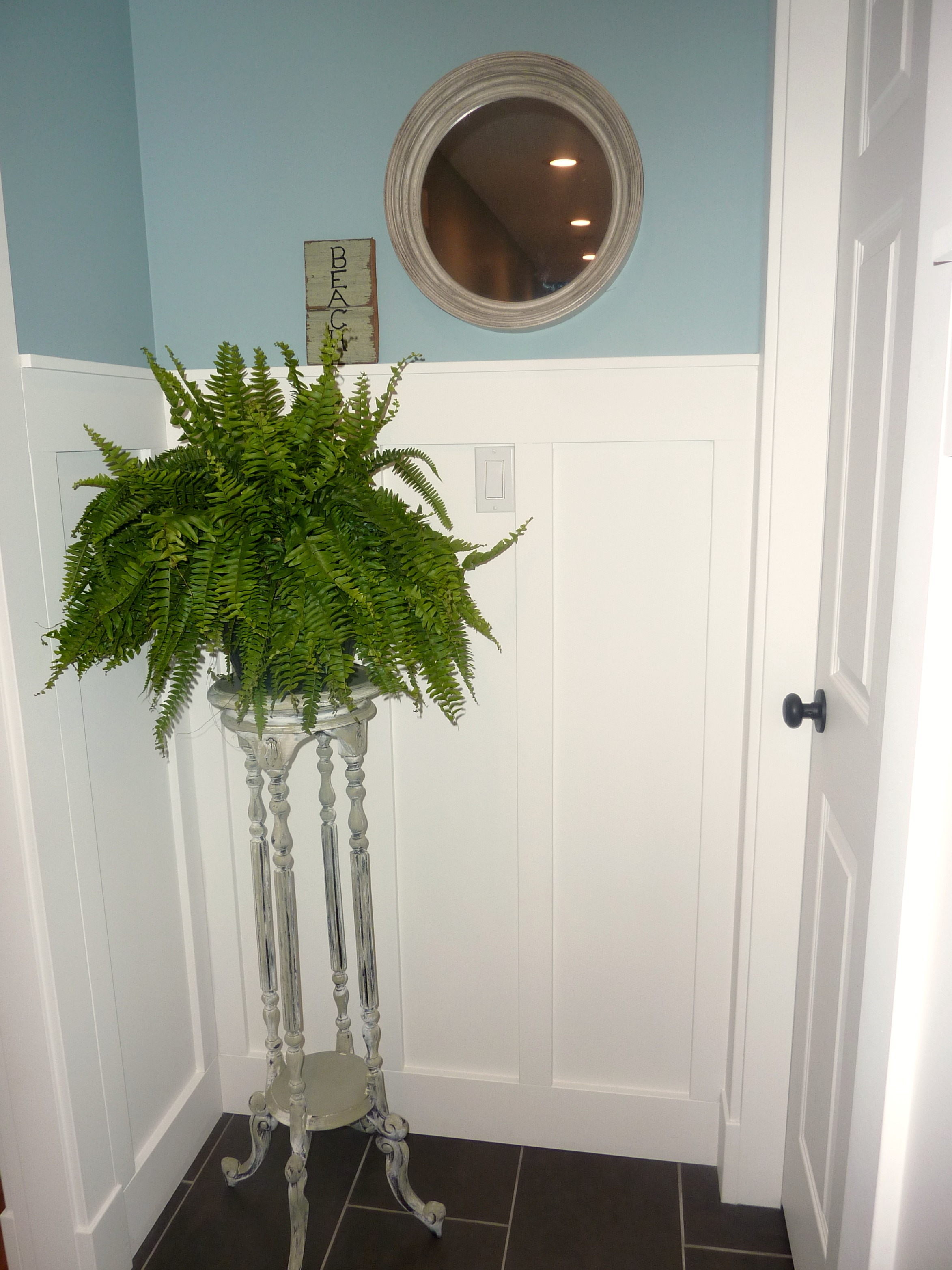 The plant stand and mirror at the end of the hall.