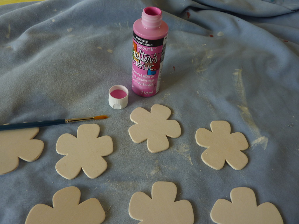 Using pink paint on little wooden flowers.