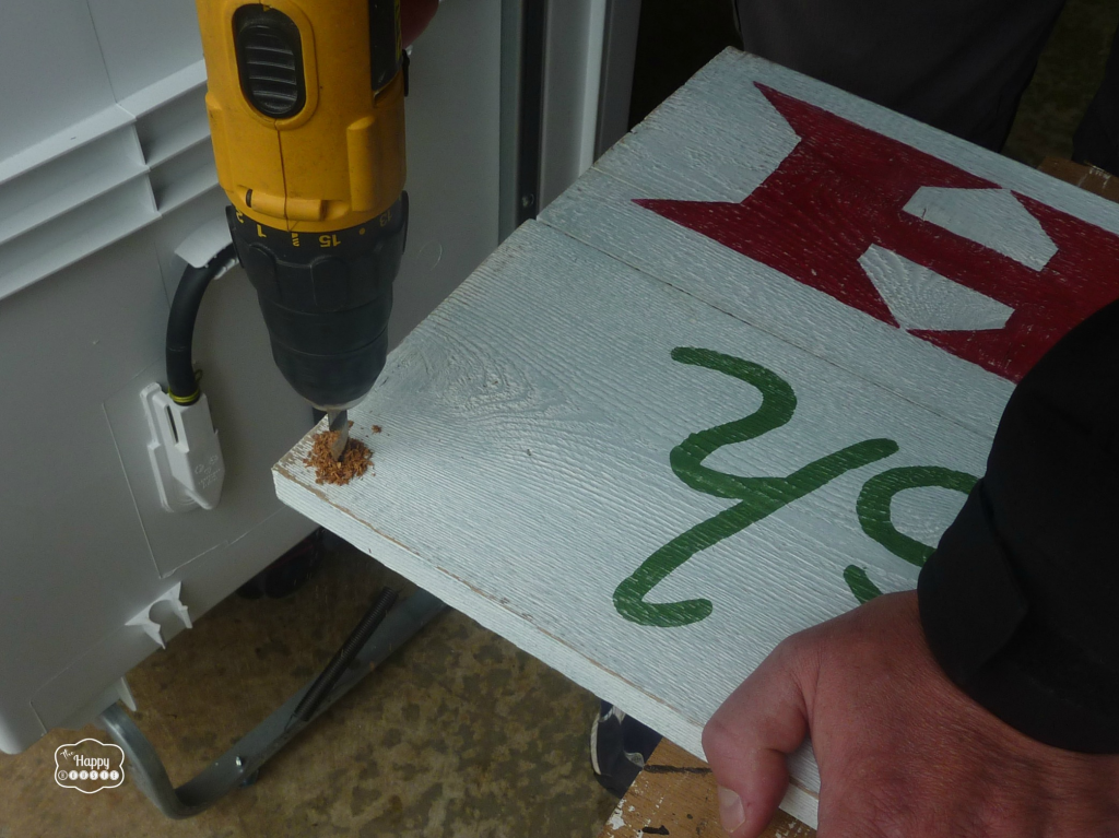 Drilling holes into the sign for hanging.