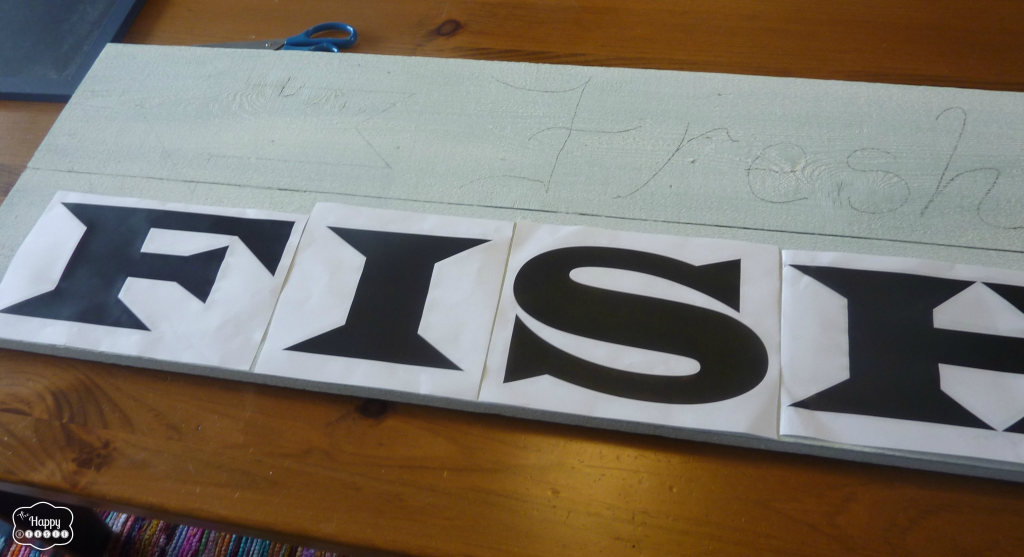 Putting the stenciled letters onto the wooden board.