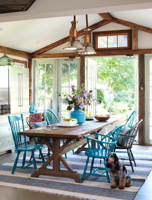 A long dining room table with blue chairs and a dog beside them.