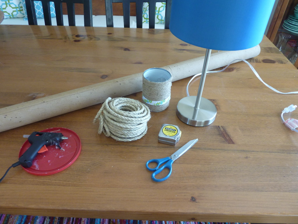 A hot glue gun, scissors, rope, a measuring tape and the lamp on a table.