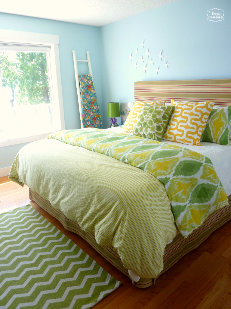 Mixed pattern bedding in yellow and green with coordinated throw pillows on the bed.
