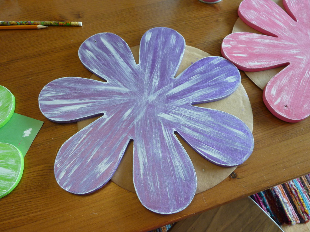 The 3 flowers in pink, purple and green drying on the table.