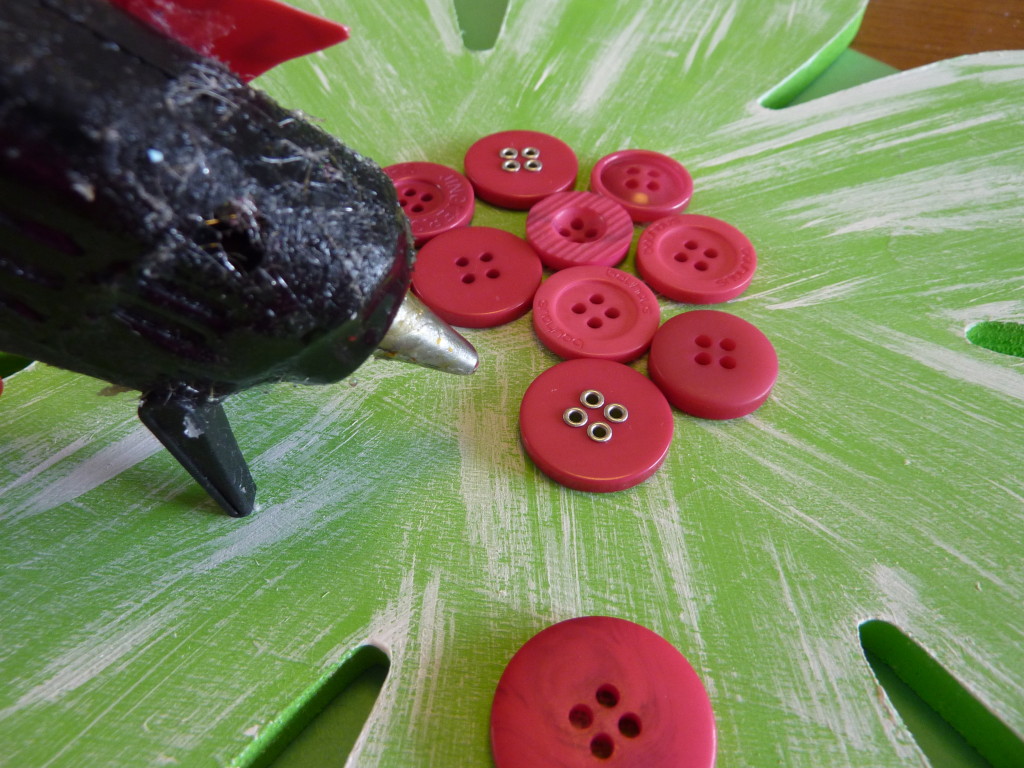 Using the hot glue gun to glue the buttons in the centre of the flowers.