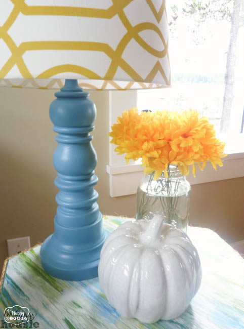 A blue lamp and white pumpkin is on a side table in the living room.