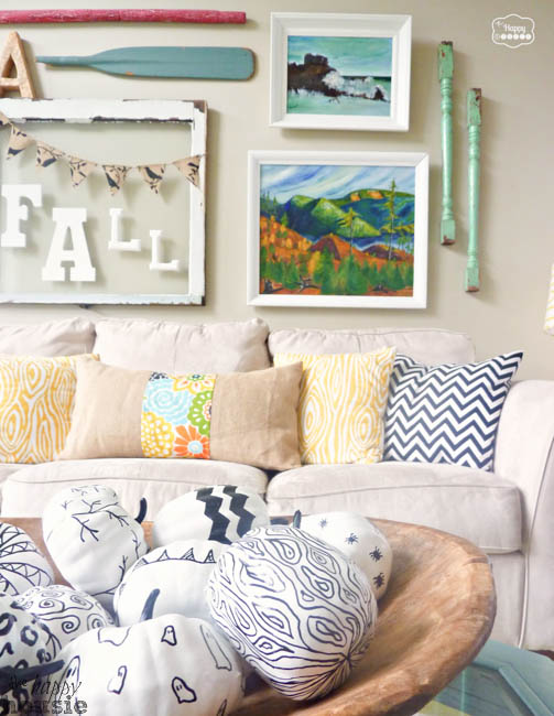 A gallery wall above the couch with a picture that says FALL plus oars and scenery pictures.