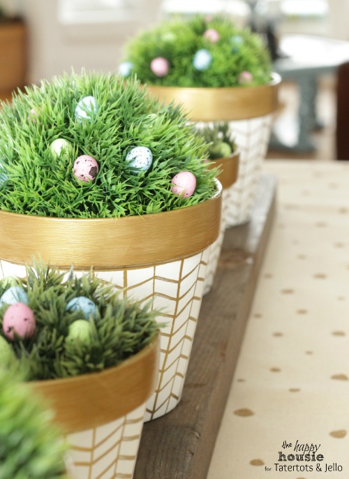 The white and gold pots with greenery in them and chocolate Easter eggs.