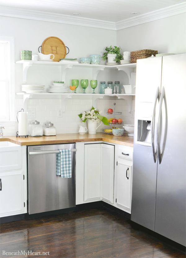 A white kitchen with open shelving and stainless steel appliances.