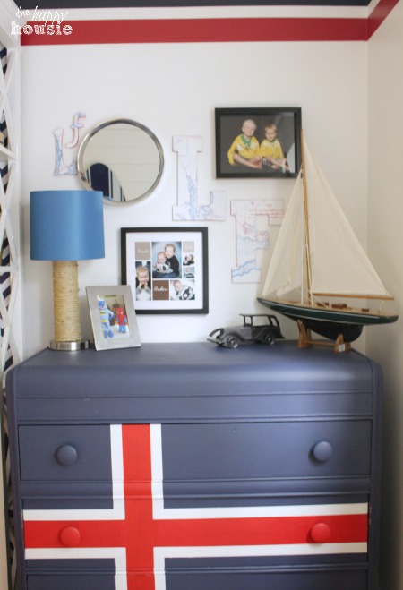 A gallery wall with pictures of the boys, a model boat is on the dresser.