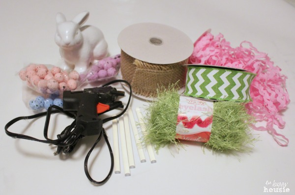 A hot glue gun, ribbon, a white Easter bunny on the table.