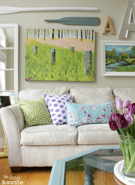 A white couch with spring inspired pillows and paddles on the wall.