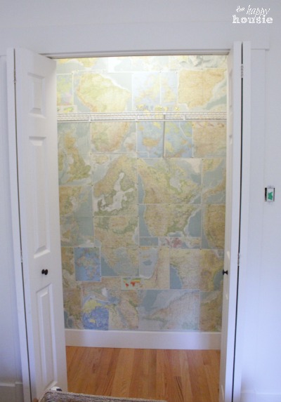 The opened closet door looking into the back wall with the map wallpaper.