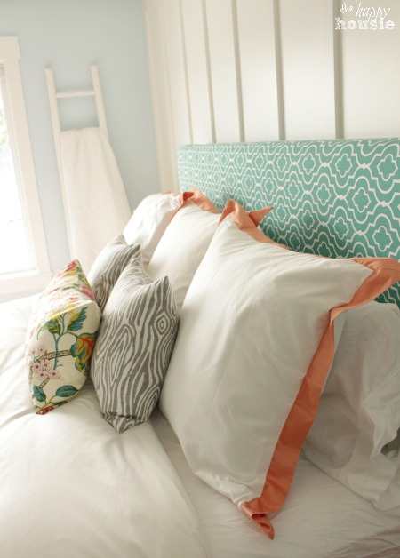 White bedding with peach trim on the pillow cases.