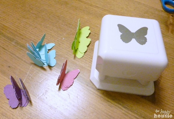 DIY Butterfly Lantern Light Fixture and paper butterflies beside it on the table.