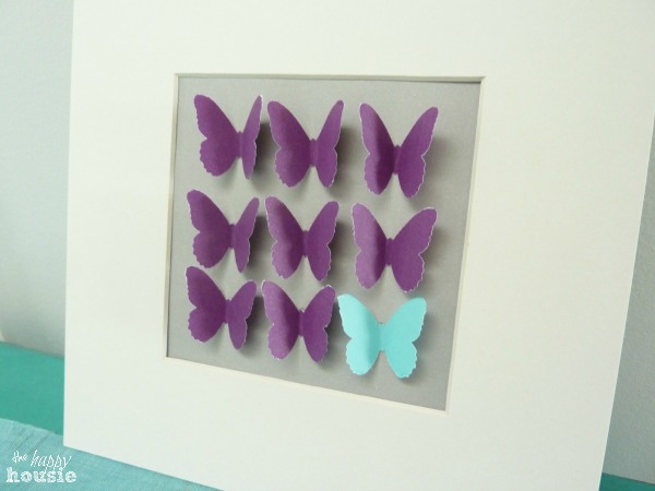 All purple and one blue butterfly glued to the card stock in the frame.