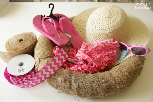 A burlap wrapped wreath with a summer hat, flip flops, sunglasses.