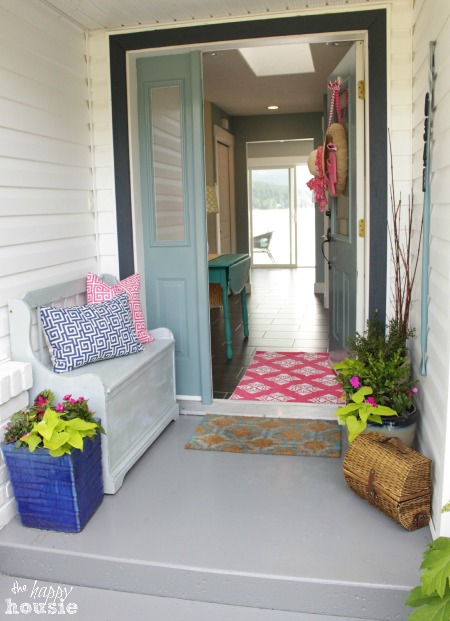 The front porch with a bench and potted plants.