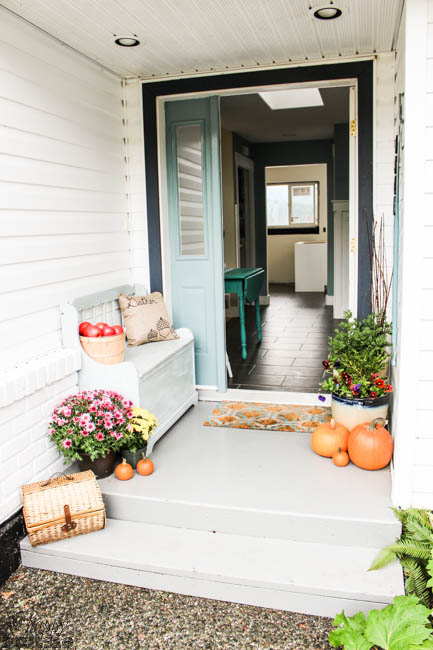 The front porch decorated with pumpkins, and planters.
