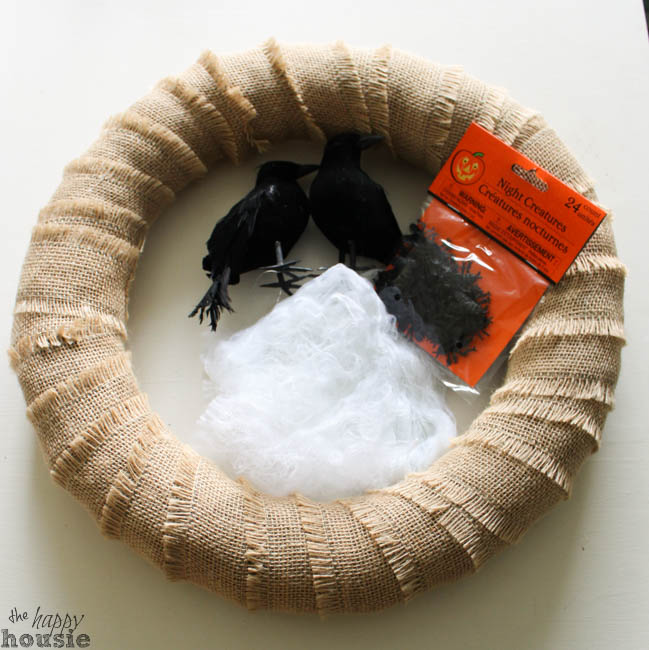 A burlap wrapped wreath, black crows and cotton supplies laid out.