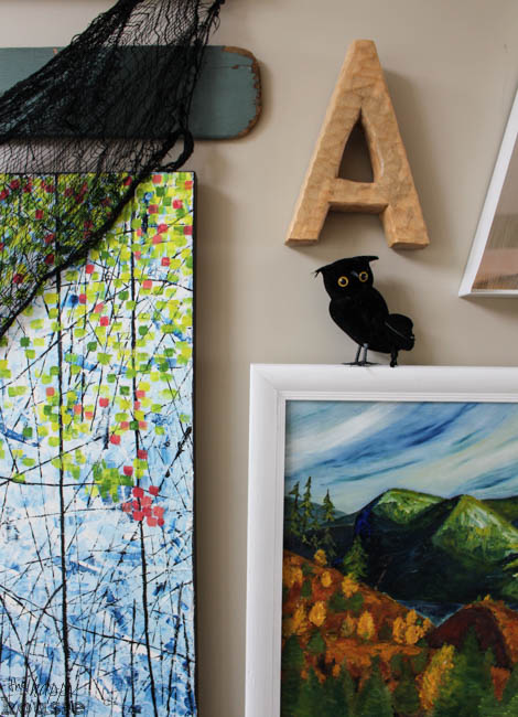 A black owl is on the picture frame on the wall.
