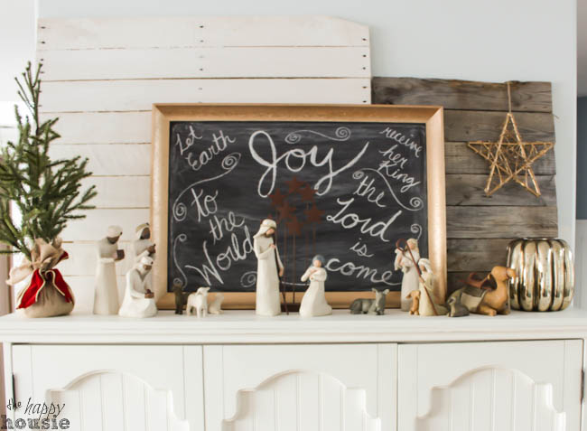 A chalkboard is filled with Christmas words with a nativity scene in front of it.