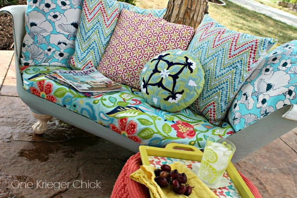 A cast iron bathtub turned into an outdoor couch with colourful pillows.
