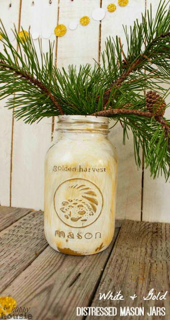 A distressed mason jar filled with evergreen branches.