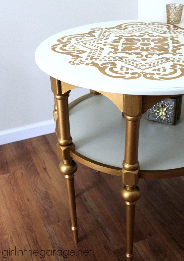 A white coffee table with the legs painted gold and the top has a design in gold on top.