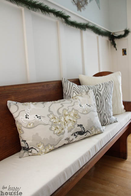 A wooden bench with throw pillows on it.