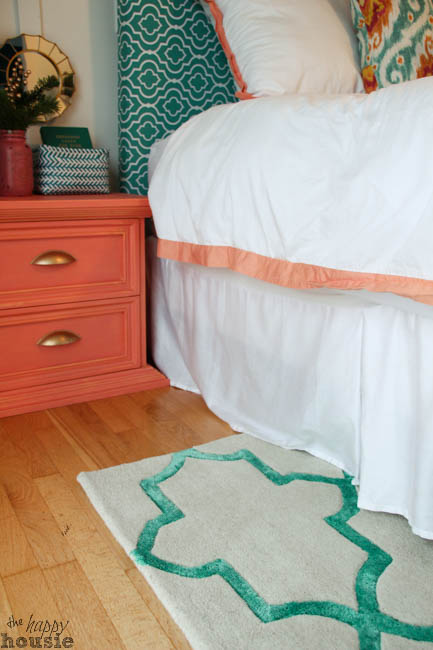 The green trellis rug in the bedroom beside a coral nightstand.