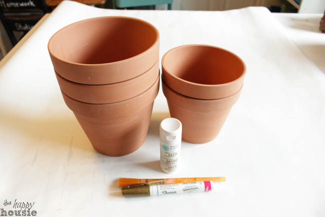 Clay pots, a gold pen and a brush on the table.