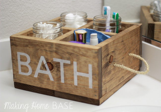 A wooden bathroom caddy with handles made of rope.