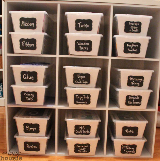 A shelf with clear bins and labels on the bins.
