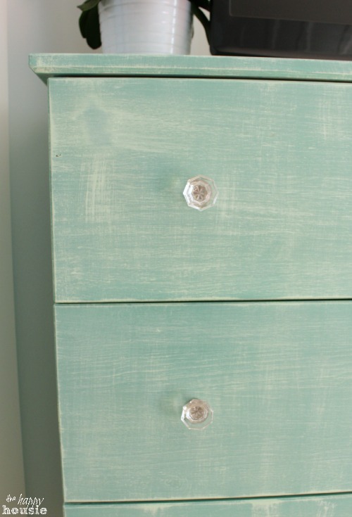 A soft light green dresser with glass knobs.