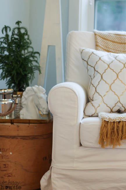 A white couch with white and gold pillow.