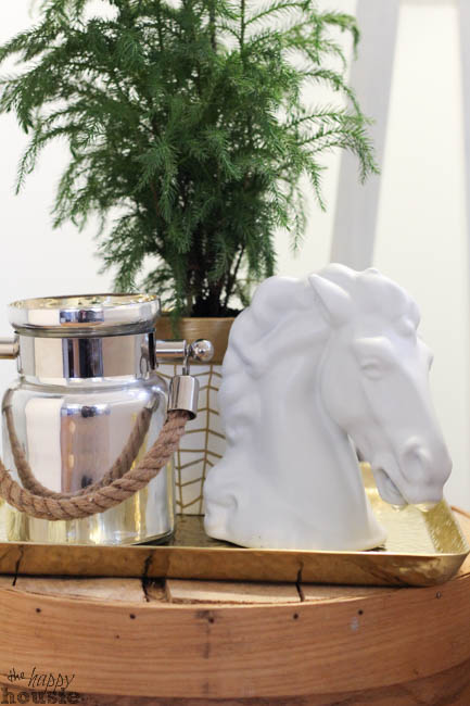 A white horse head is on a gold tray beside a potted plant.