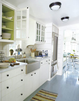 A cottage kitchen with soft green interior in the cupboards and a farmhouse sink.