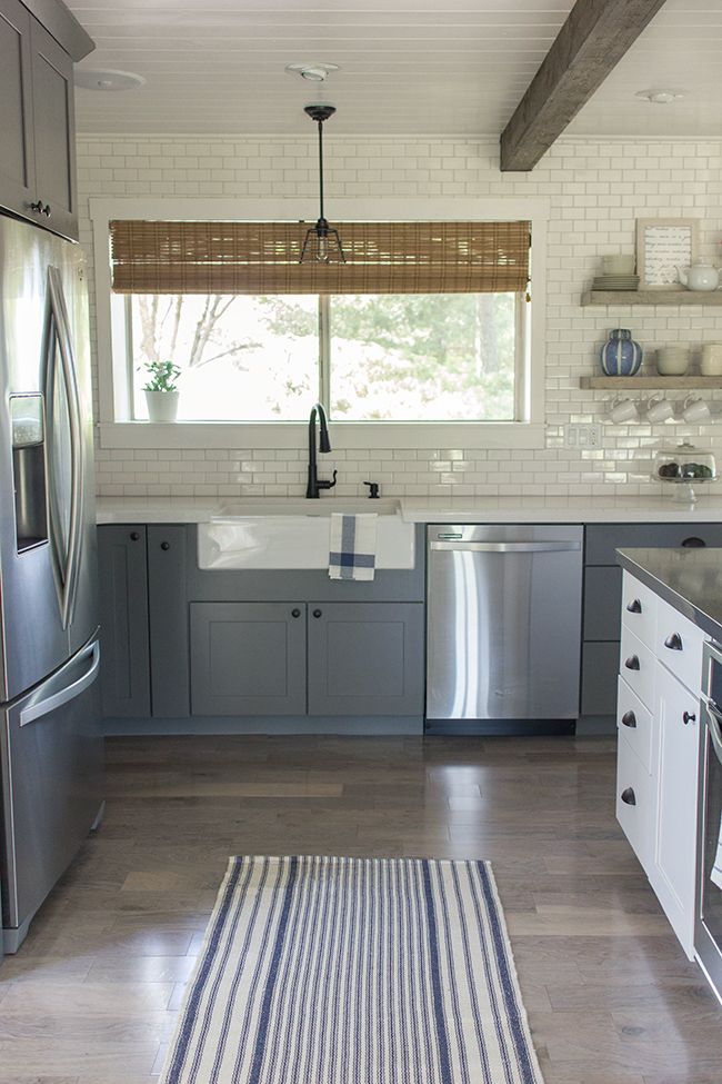 Blue/grey cabinets in the kitchen with a rug runner.