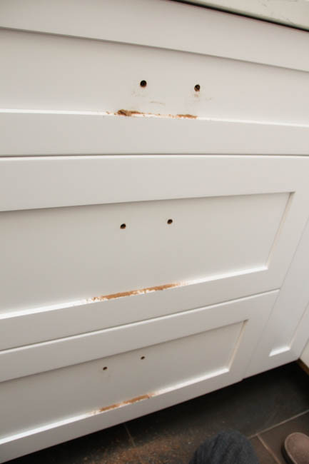 The drilled holes into the white cabinet.