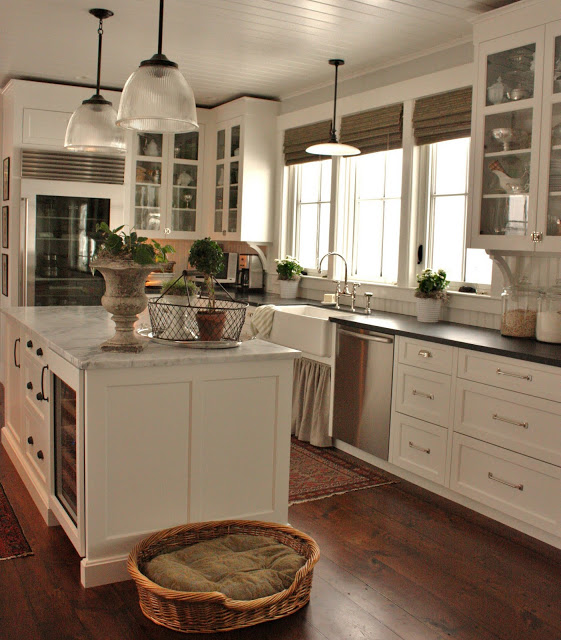 A wire basket is on the white kitchen island with a marble top.
