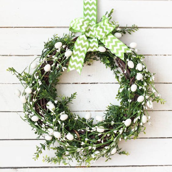 A wreath with faux greenery and white flowers.