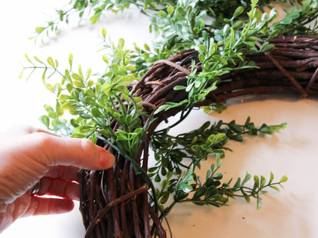 Wrapping the faux greenery around the grapevine wreath.