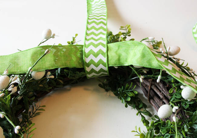 Tying a green and white ribbon to the top of the wreath for hanging.