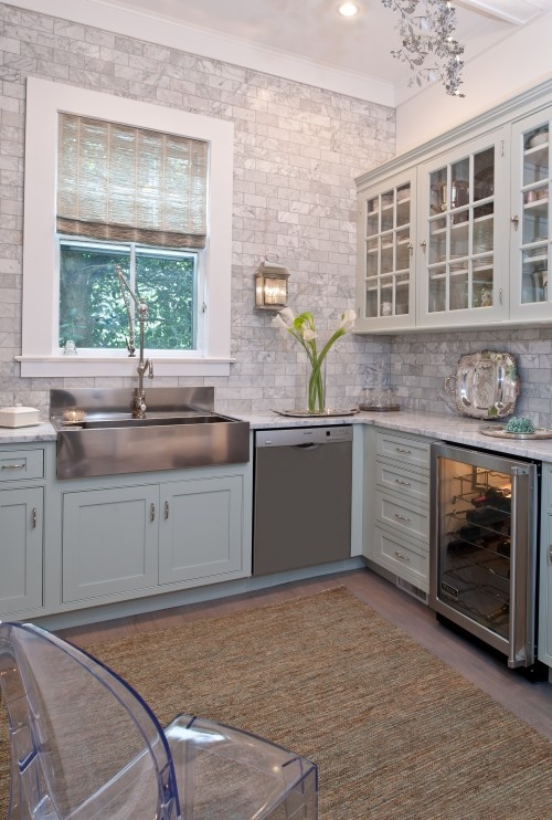 Grey subway tile, soft lighting and mint green cupboards are in the kitchen.